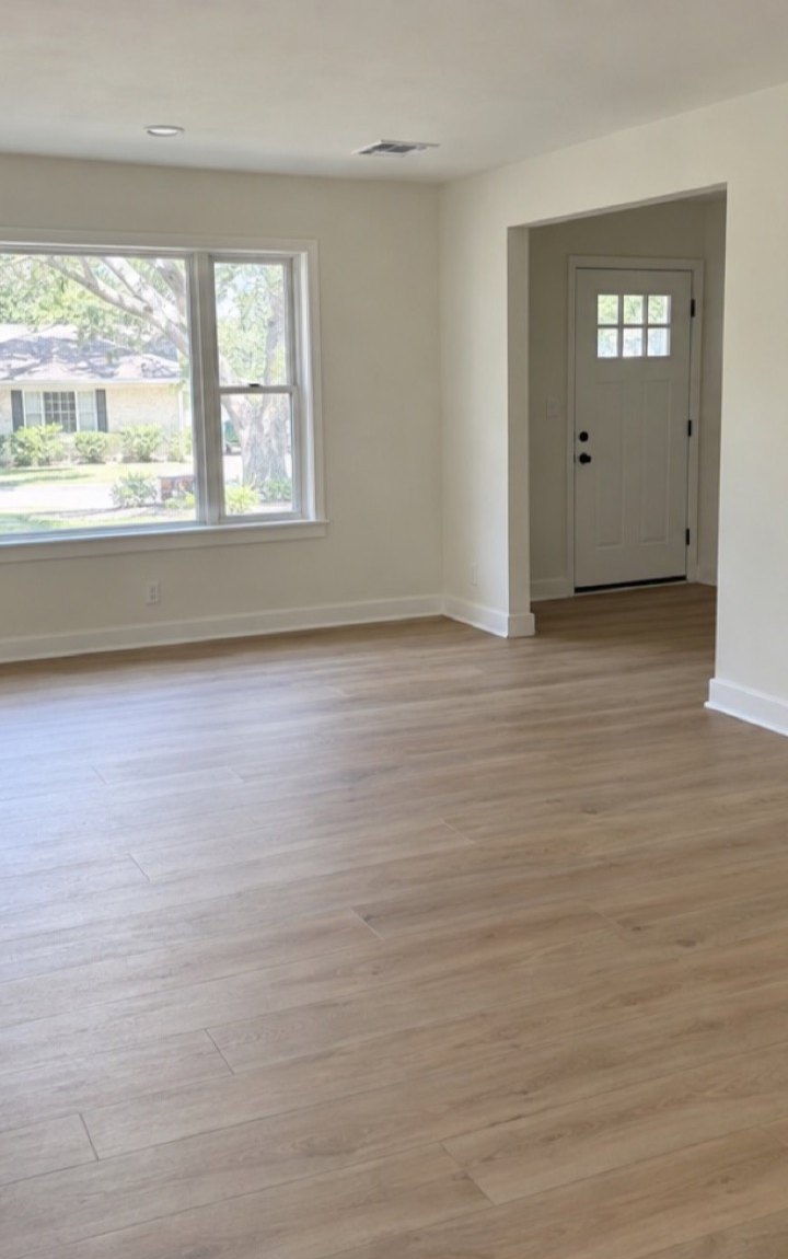 A borrower's draw photo, taken on site: the living room painted in two coats with the trim cut in, and new wood flooring laid.